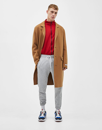 Как и с чем носить: коричневое длинное пальто, красный свитер на молнии, серые спортивные штаны, разноцветные замшевые кроссовки